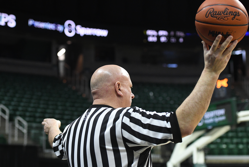 A basketball official awaiting an inbounds pass points in the direction in which play will resume.