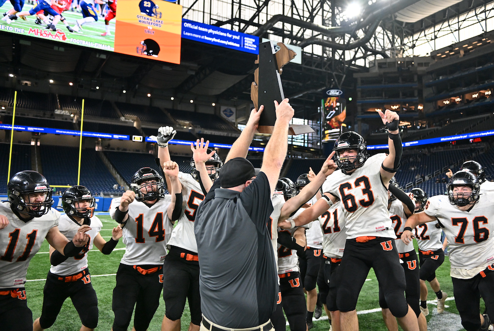 Ubly coach Eric Sweeney presents the Division 8 championship trophy to his team Saturday morning at Ford Field. 