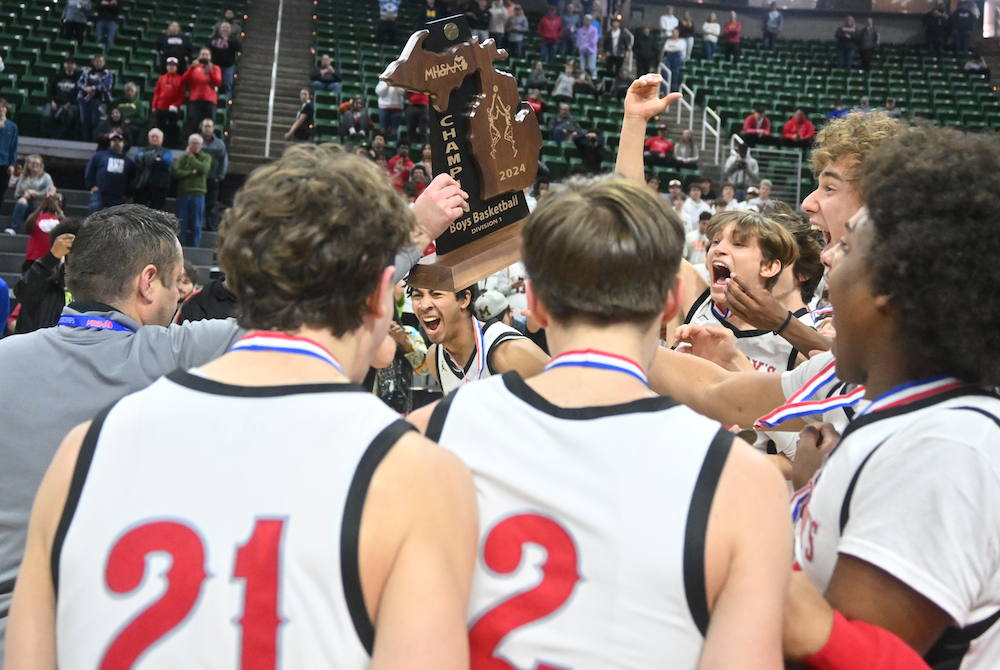 Orchard Lake St. Mary’s coach Todd Covert presents the Division 1 championship trophy to his players Saturday at Breslin Center.