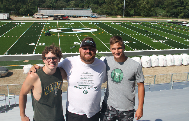  From left: Thomas Kurtz, coach Robbie Hattan and senior Daniel Wells stand together in the team’s new stadium. 